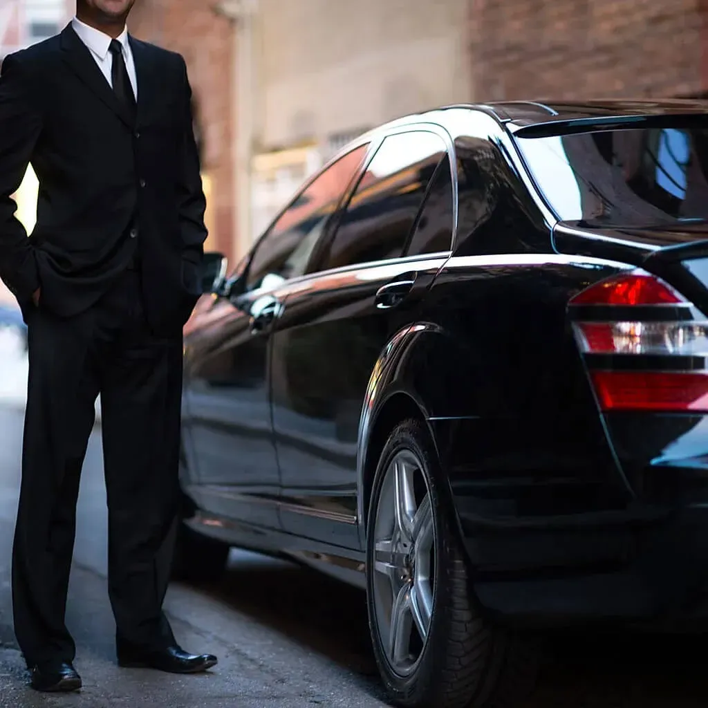 Motorista junto a uma limousine preta de luxo